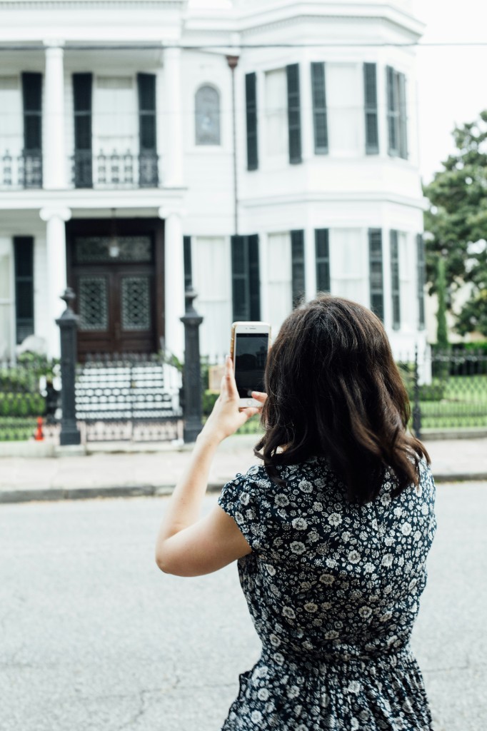 Person documenting a property with a smartphone from the sidewalk